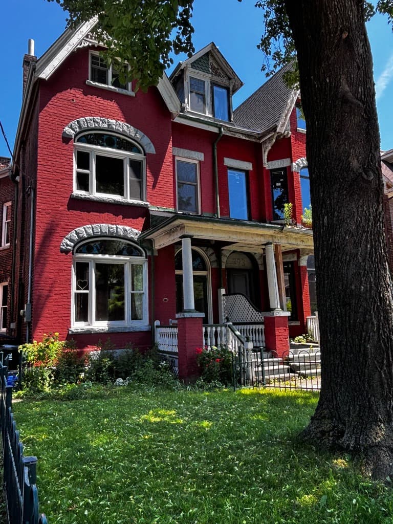 Current view of the vibrant red Victorian house at 393 Manning Ave, beautifully preserved with original architectural details