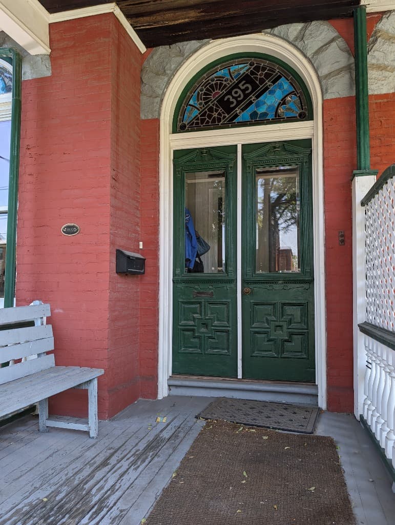Green entrance door of 395 Manning Avenue with stained glass transom above