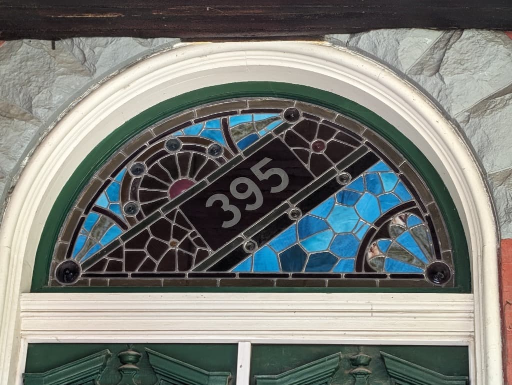 Intricate blue stained glass transom showing house number 395, representative of Victorian craftsmanship