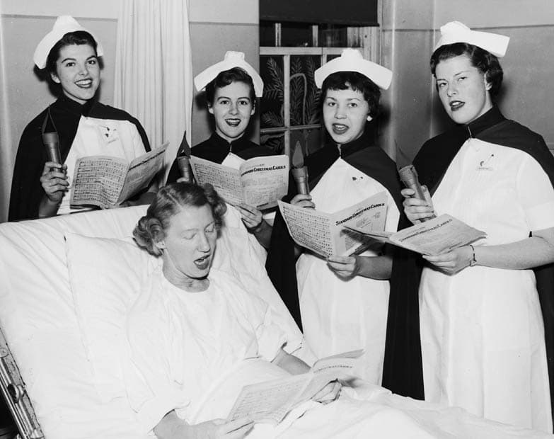 Four nurses at the Toronto Western Hospital gathered around a patient, circa 1955