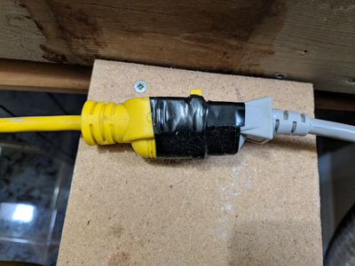 Extension cord connection secured with black electrical tape - first example